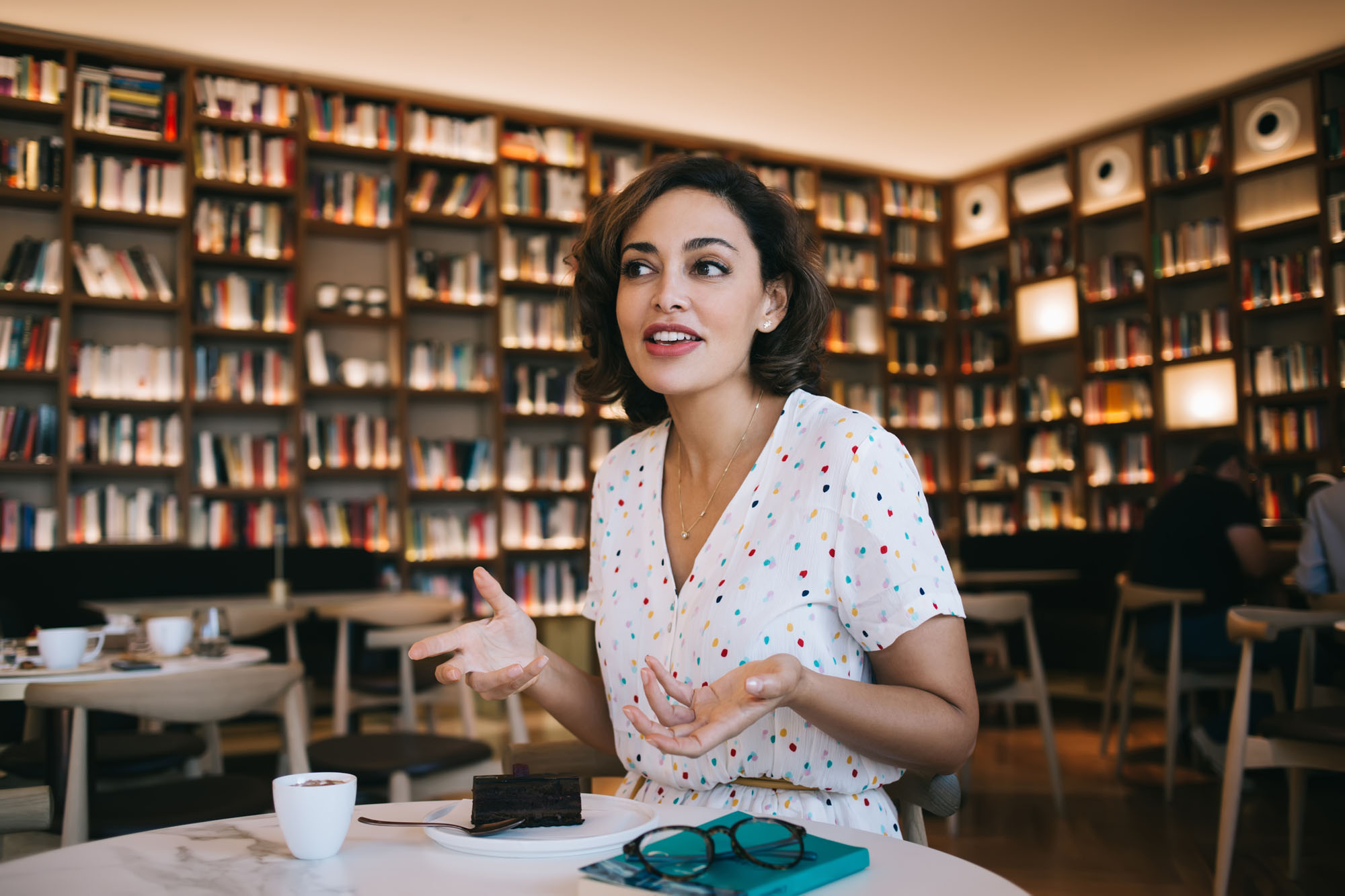 Perplexed woman in cafe with bookshelves Perplexed woman in cafe with bookshelves