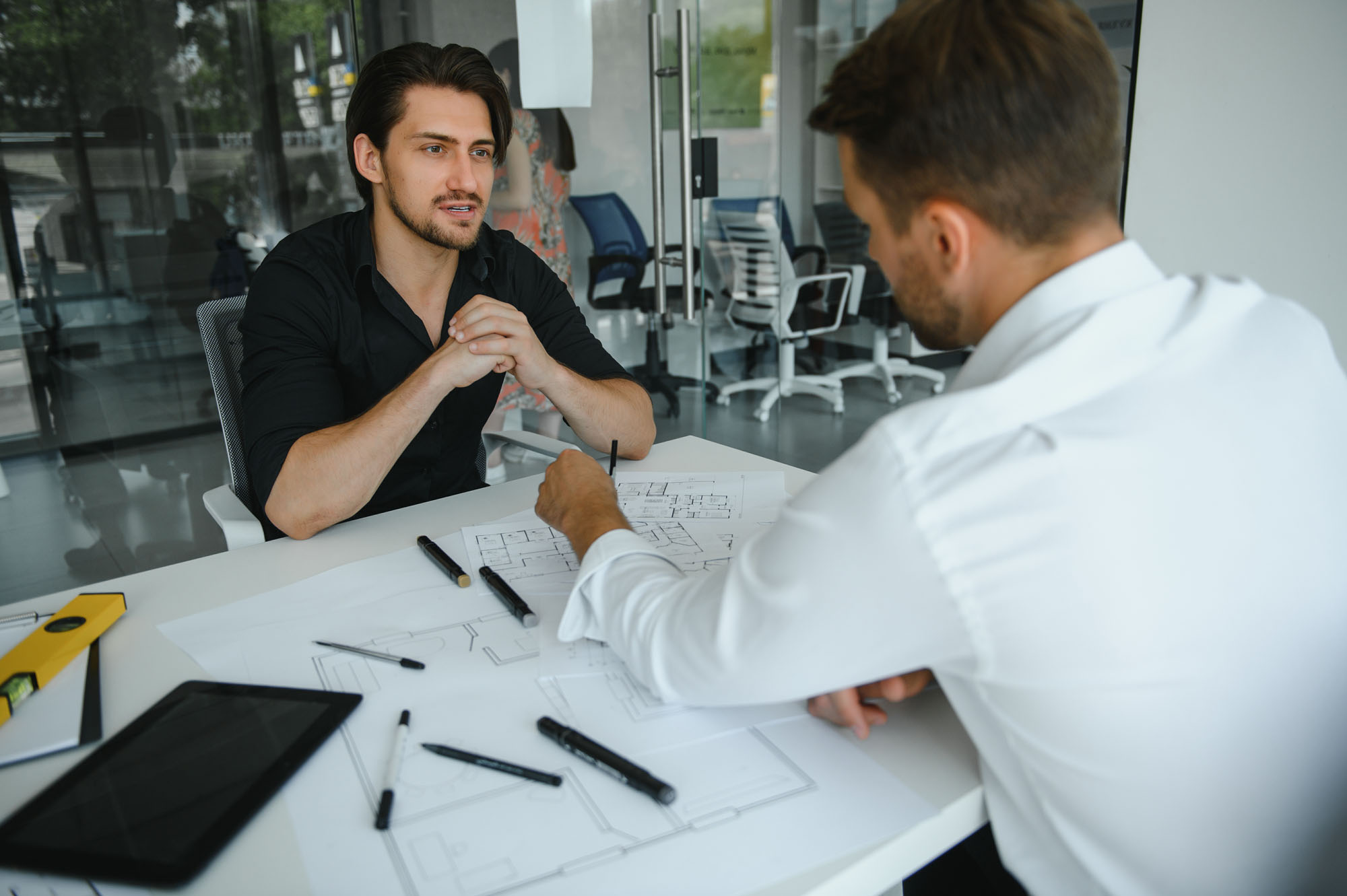 Two engineering working together and using digital tablet looking blueprint and analysis with architectural plan on desk